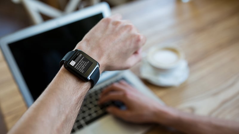 hand-wearing-smartwatch-using-laptop-coffee-shop (1)
